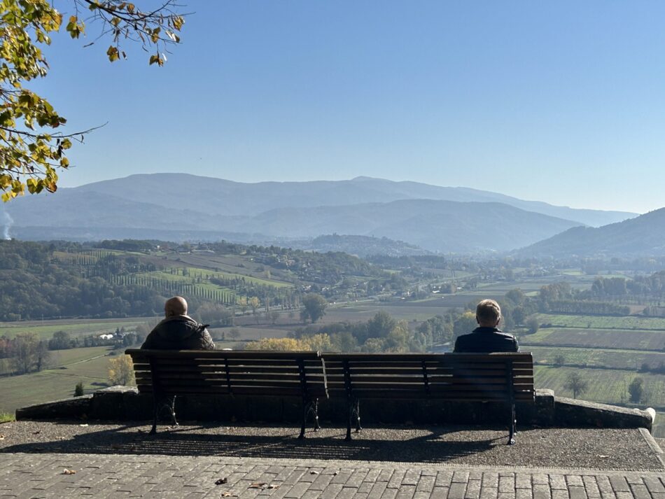 Due persone sedute su una panchina osservano il paesaggio dall’alto