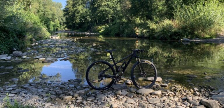 MTB appoggiata sul greto del fiume Arno tra pietre e acqua
