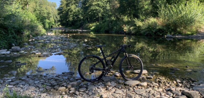 MTB appoggiata sul greto del fiume Arno tra pietre e acqua